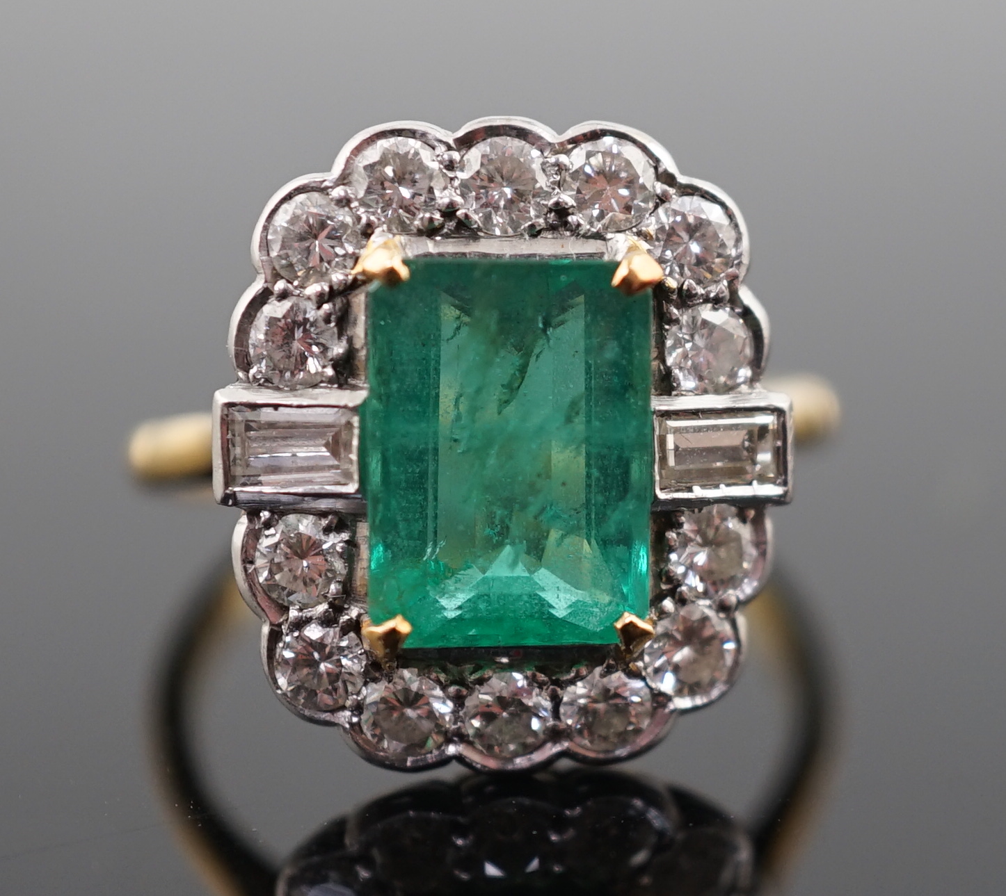 An Art Deco style yellow metal, emerald and diamond set oval cluster ring